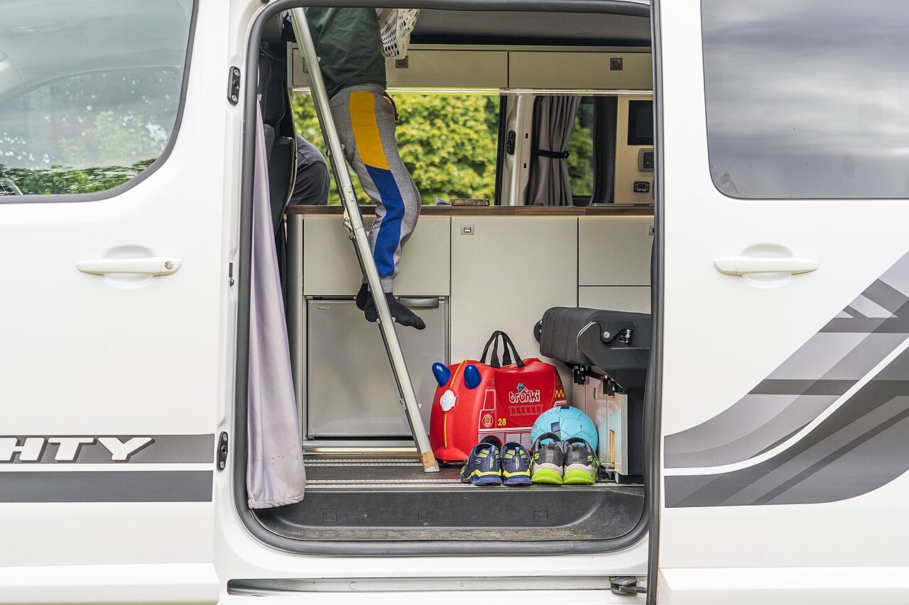 Travelers relaxing at the open rear doors of their campervan